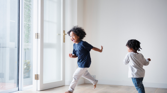 Two young children chasing each other inside of a room