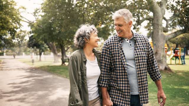 Older couple walking outside on a sunny day and holding hands