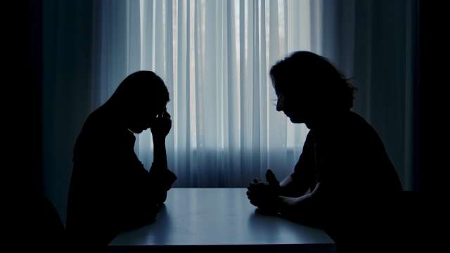 Silhouette of two people talking.