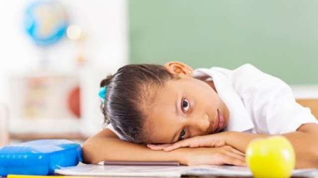 Young girl in school with head on desk