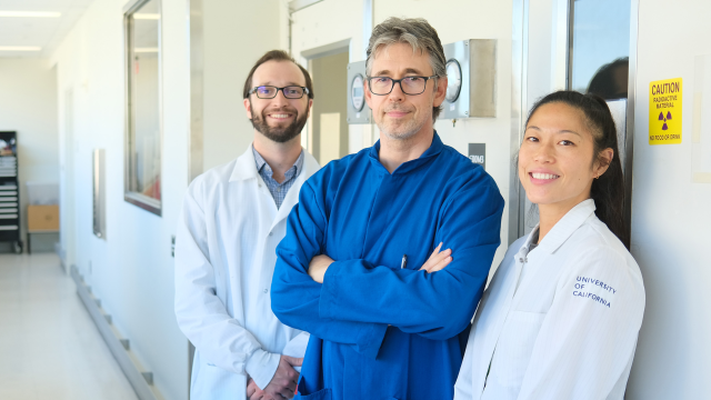 Two male doctors and one female doctor smiling in a hospital hallway