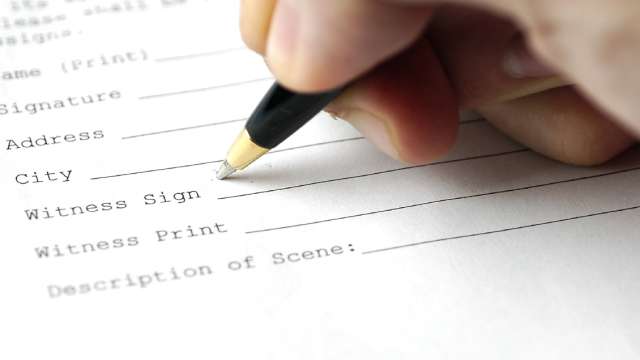 Person signing their name with a pen