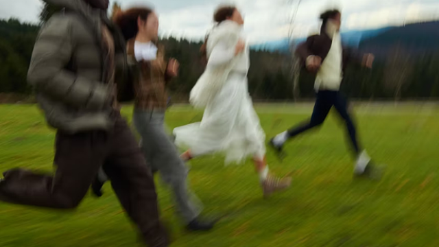 a blurred perspective of four people running in the grass