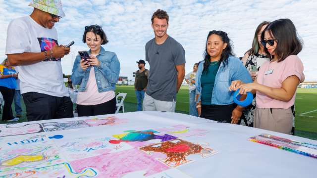 Chargers wide receiver Ladd McConkey looks at the Crucial Catch mosaic with guests.