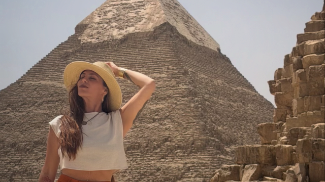 A woman stands in front of a pyramid in Egypt.