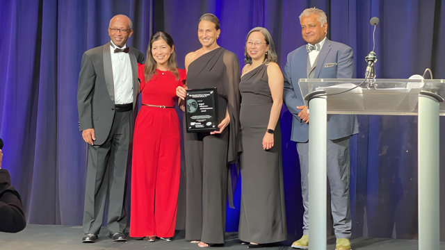 Dr. Catherine Juillard receives the ACS/Pfizer Academic Global Surgeon Award on stage.