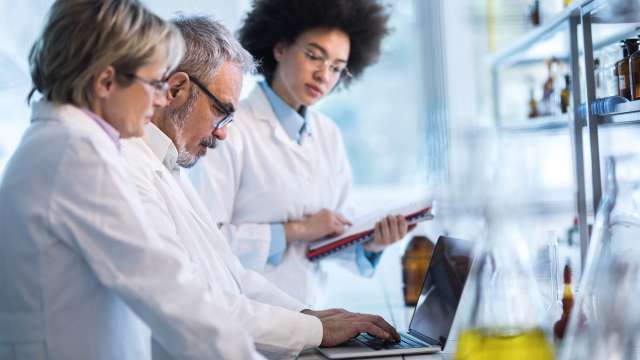 Researchers standing and discussing a presentation in a lab