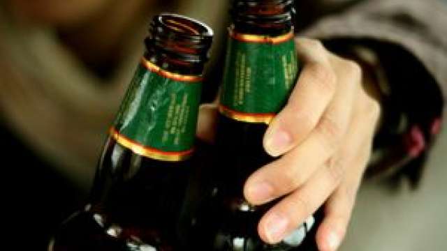 Two beer bottles with a hand reaching toward them.