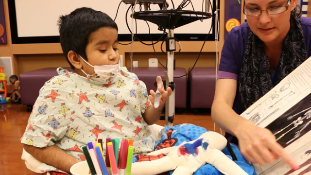 A Child Life Specialist reads a book to a UCLA Health pediatric patient.