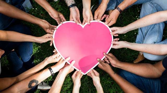 People in a circle holding a heart
