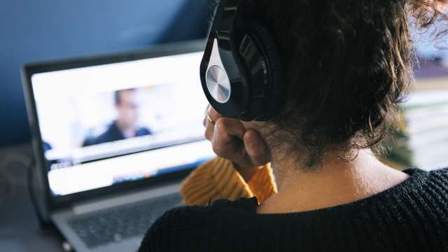 woman with headphones watching video on laptop