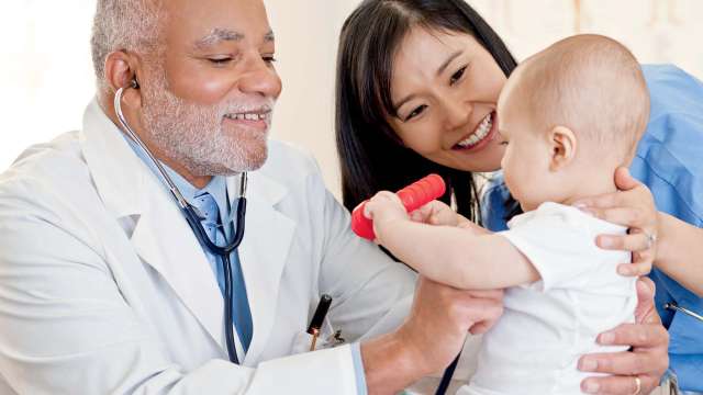 A mom holding a neck of her baby and showing the baby to a doctor.