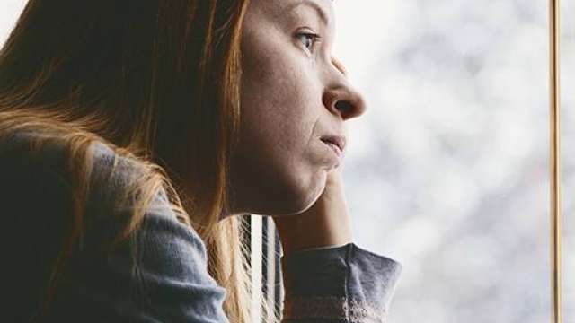 Young woman looking sadly out window