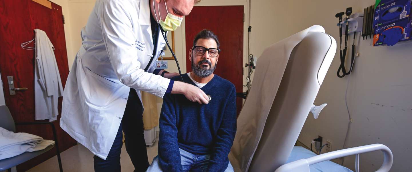 Doctor checking man's heart with stethoscope