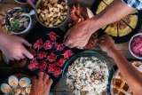 Vertical top view of friends eating together on a wooden table full of food