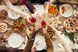 a photo of people cheers-ing holiday beverages at a dinner table