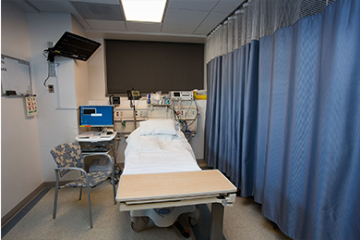 Fetal Diagnostic Unit showing a bed, a patient's tray, visitors chair,, a monitor, and medical equipment behind the bed.
