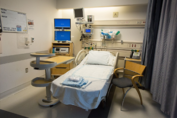 Labor & Delivery Recovery Room. A bed, patient tray, visitor chair, monitors, and some other medical equipment behind the bed.