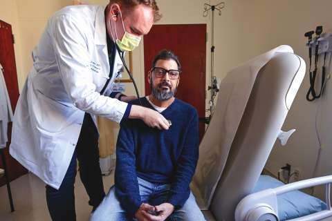 Doctor checking man's heart with stethoscope