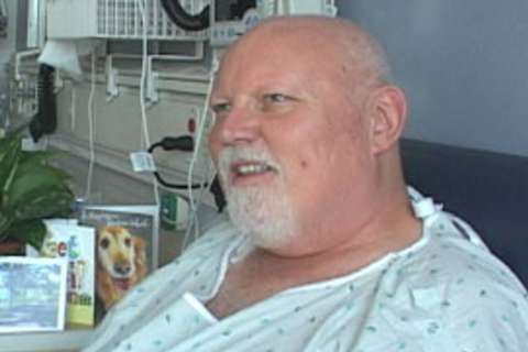 Kidney Transplant Patient seated in hospital bed wearing a gown
