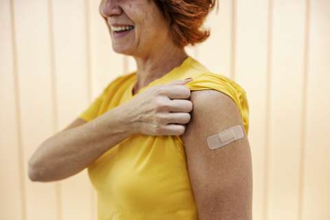 Woman shows place on arm where she got her vaccine