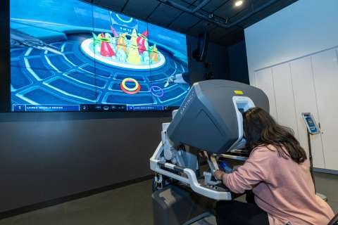 A photo of third-year medical student Amulya Vadlakonda using a robotic surgery simulator at Rosenfeld Hall opening event.