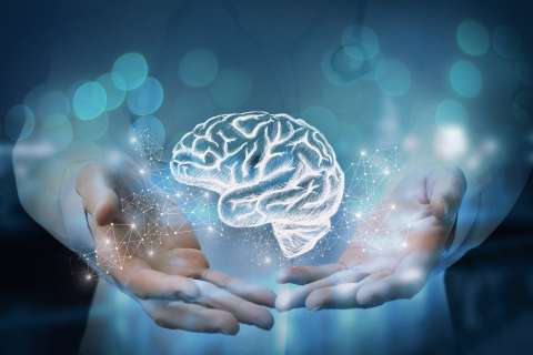 Two hands cradling a glowing holographic brain against blue bokeh background.