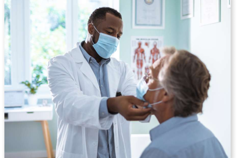 Doctor examining and patient, both wearing face masks.