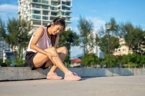 Runner sitting down massaging shins due to shin splints