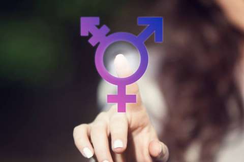 Person with long brown hair reaching out and touching a symbol that represents transgender