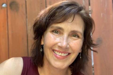 Tara Paul smiling in front of a wood panel fence