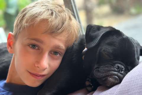 Child smiling with black dog laying together