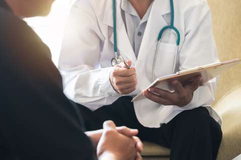 Doctor in white coat with stethoscope consulting a seated patient