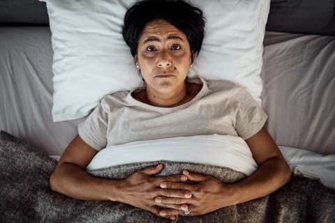 An older woman lays awake in bed.