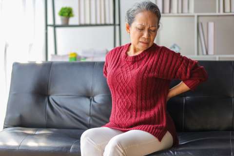 Woman sitting on a couch with back pain