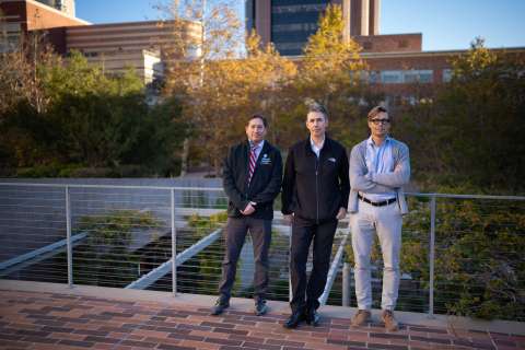 Drs. Noah Federman, Robert Damoiseaux and David Ulmert standing on a walkway surrounded by greenery and buildings.