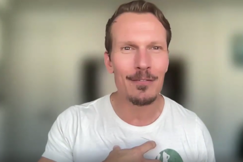A man smiles and gestures during a webinar