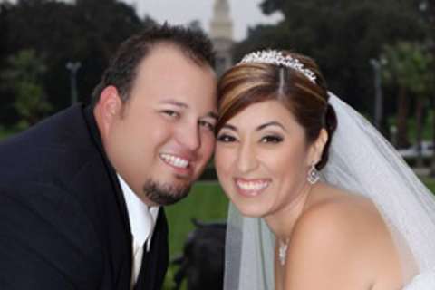Bride and groom leaning close and smiling outdoors