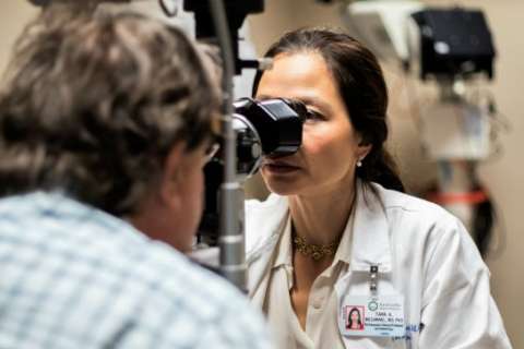 Dr. Tara McCannel performing an eye exam with a slit lamp on a patient