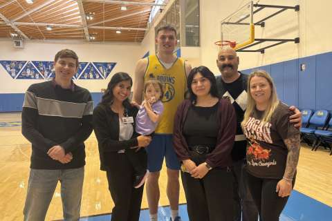 Group of several people smiling together on a basketball court