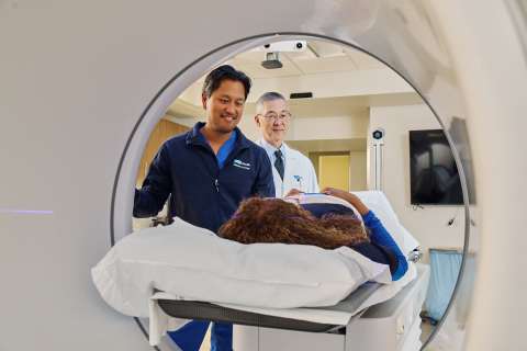 Medical scanner tunnel with two technicians loading a patient on the table