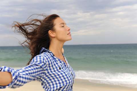 A woman feels the breeze at the beach.