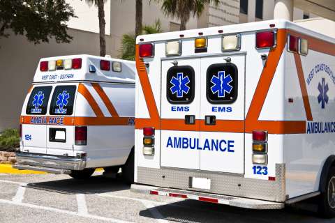 EMS Emergency trucks: two ambulances seen from rear with EMS logos and lights
