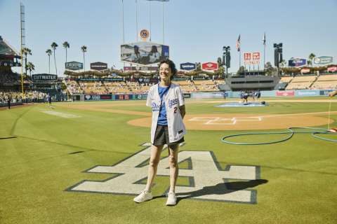 A woman stands near the LA logo on the field at UNIQLO Field at Dodger Stadium.