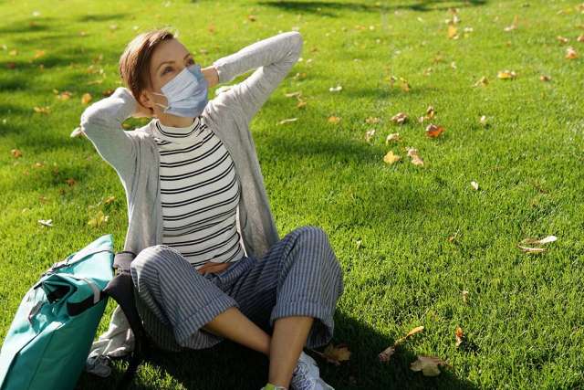Woman sitting on the grass with face mask on