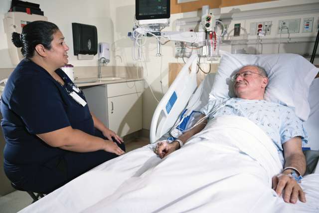Nurse speaking with a patient in a hospital room.