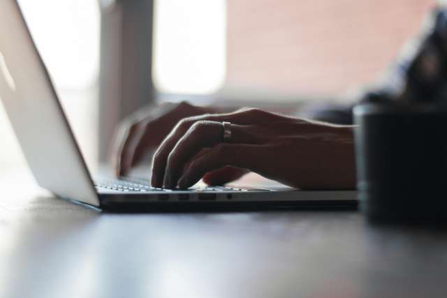 A person writes on a laptop.