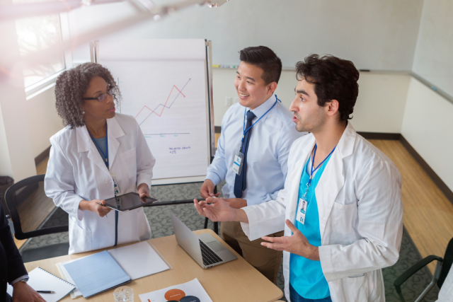 Four doctors standing at a table discussing charts