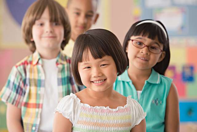Three children smiling together in a classroom