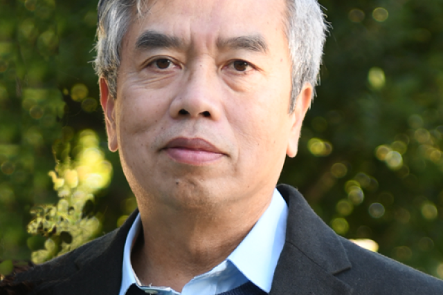 headshot of Hung Ton-That, PhD in an outdoor setting with leaves in the backgrounds